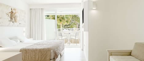 A modern hotel room with a bed, a sofa, a balcony with a table and chairs, and a TV mounted on the wall.