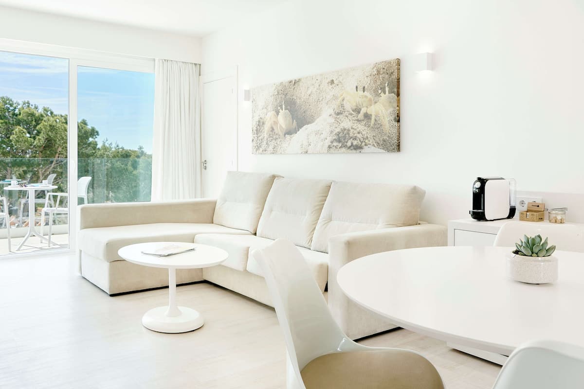 Een moderne woonkamer met een bank, een ronde tafel en een groot raam.