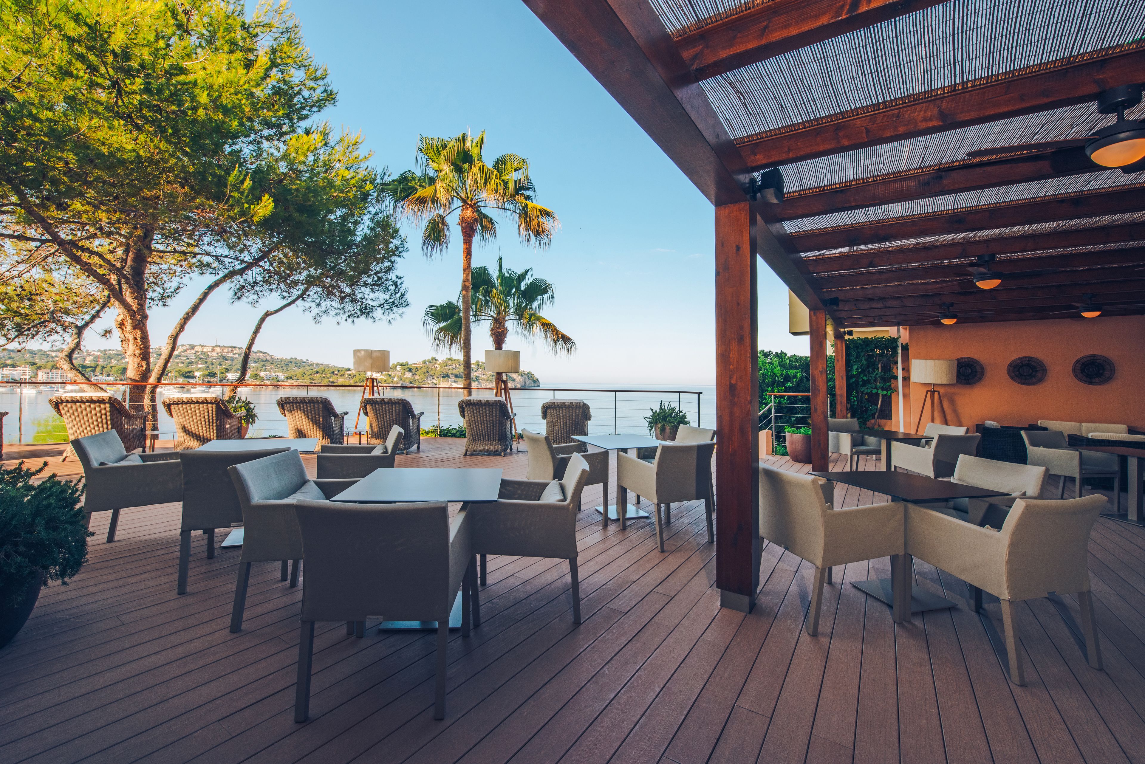 An outdoor patio with wooden flooring, wicker furniture, and a view of the sea.