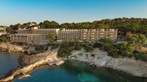 Un hôtel situé sur la côte, doté de nombreux balcons, d’un espace piscine et d’une plage rocheuse.