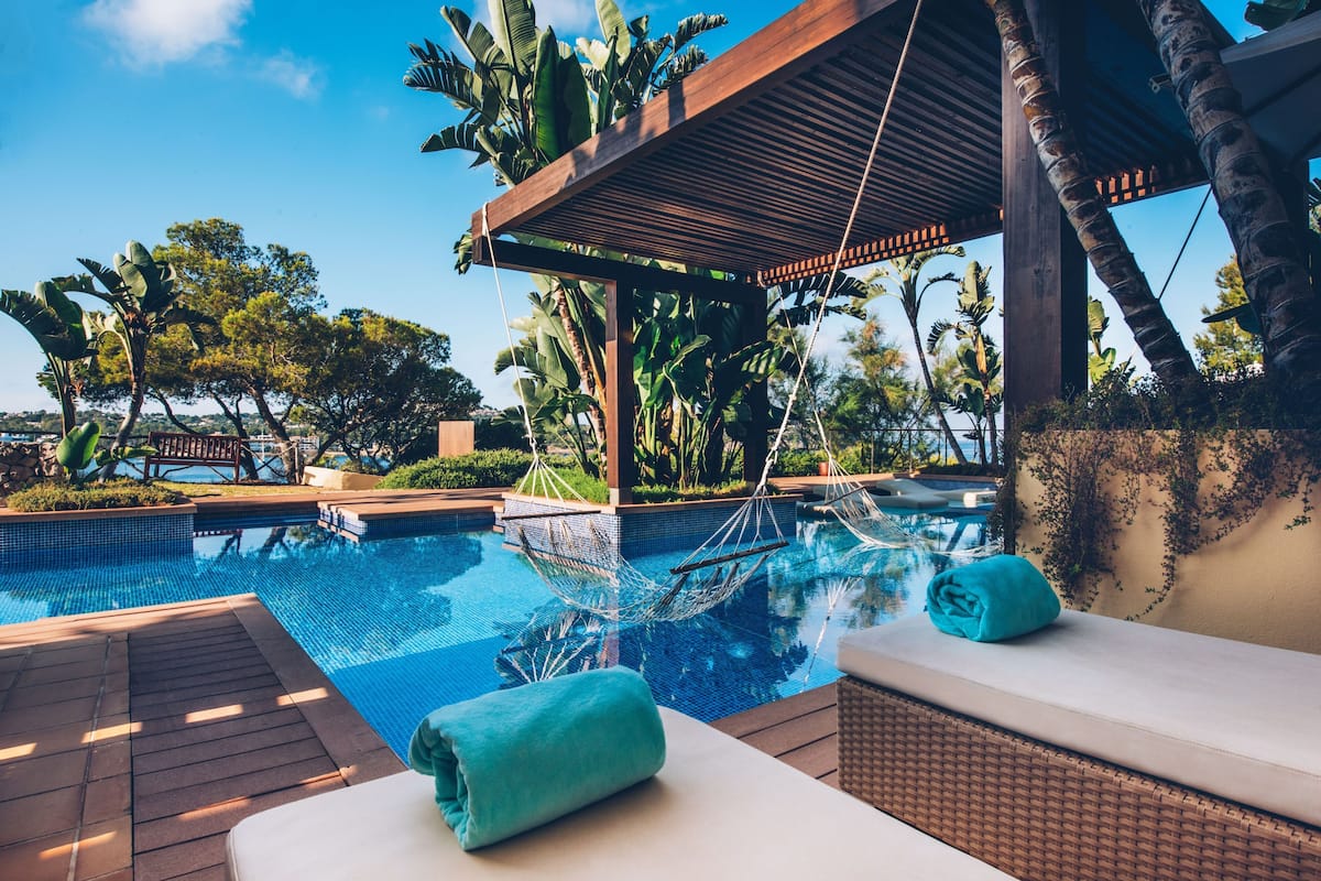 A pool area with a hammock, lounge chairs, and a view of the surrounding landscape.