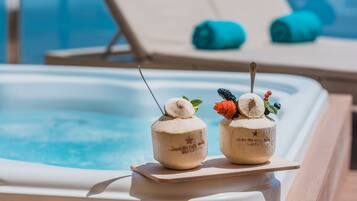 Two coconut-shaped drinks with garnishes on a poolside table.