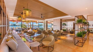 A modern hotel lobby with a long sofa, comfortable chairs, and a wooden ceiling.