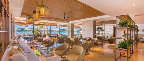 A modern hotel lobby with a long sofa, comfortable chairs, and a wooden ceiling.