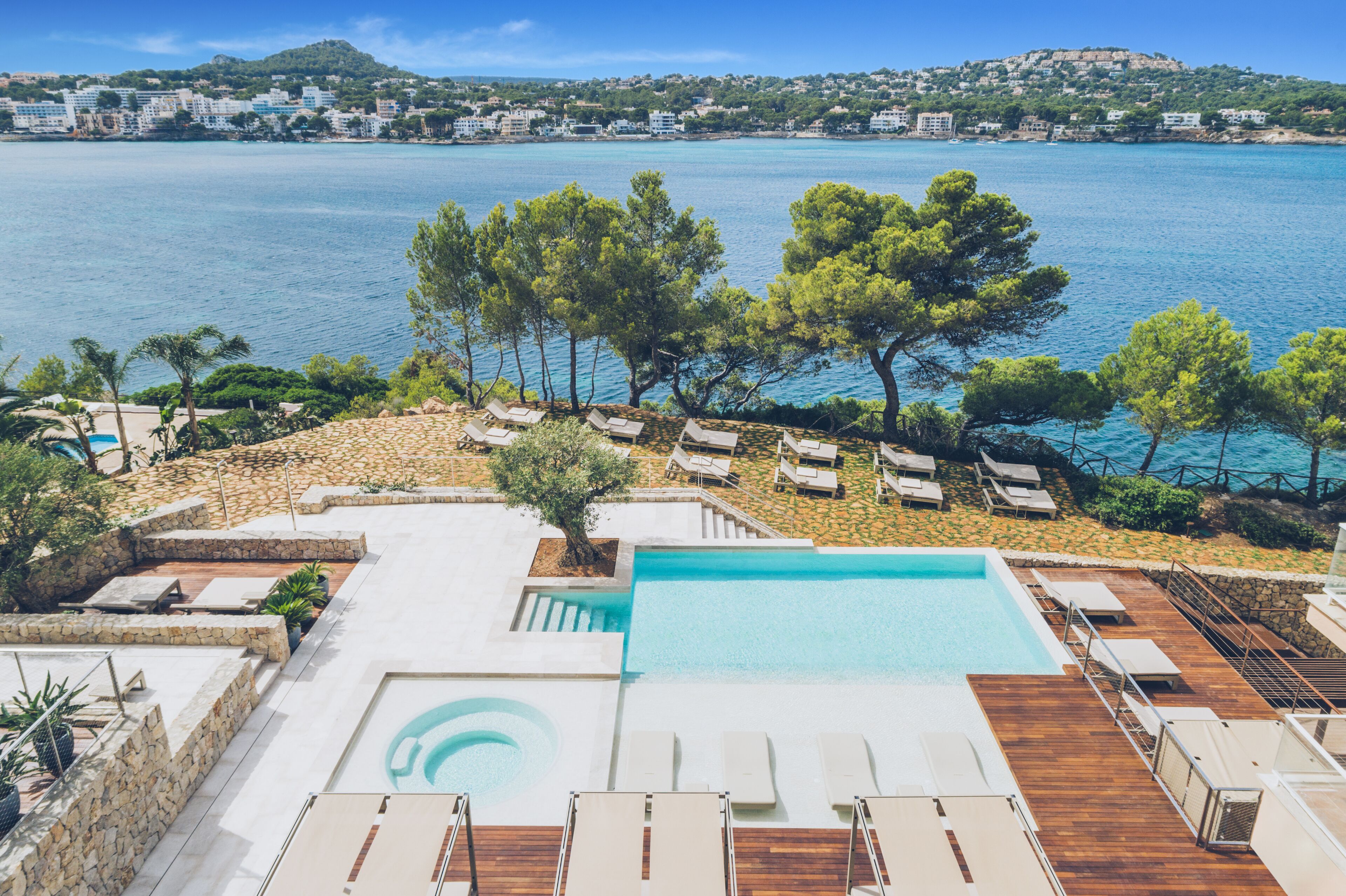 A rooftop pool with lounge chairs and a view of the sea.