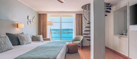 Ein Hotelzimmer mit einem großen Bett, einem Deckenventilator, Meerblick, einem Balkon und einem Fernseher.