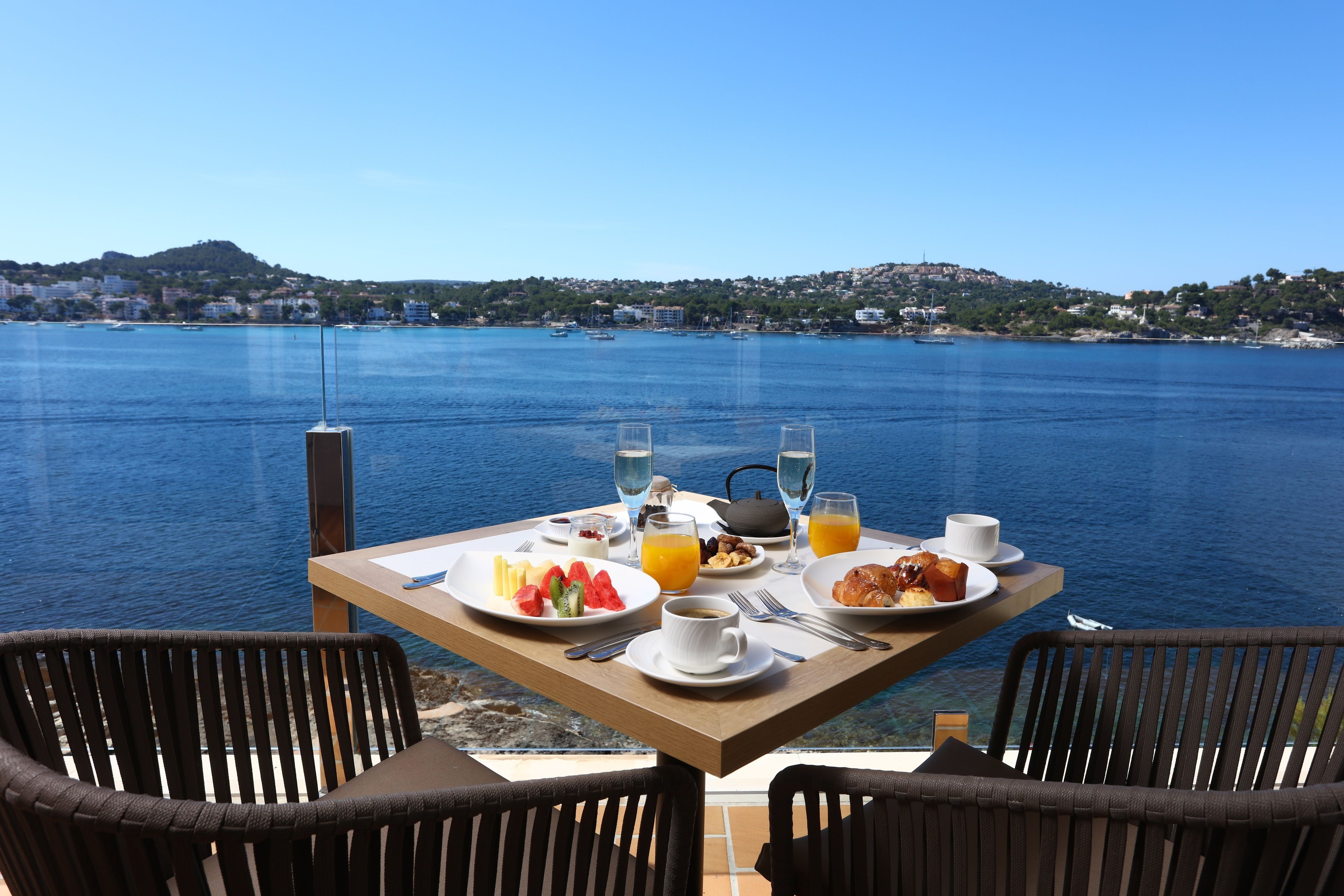 Mesa dispuesta para el desayuno con vista al mar y a las colinas.