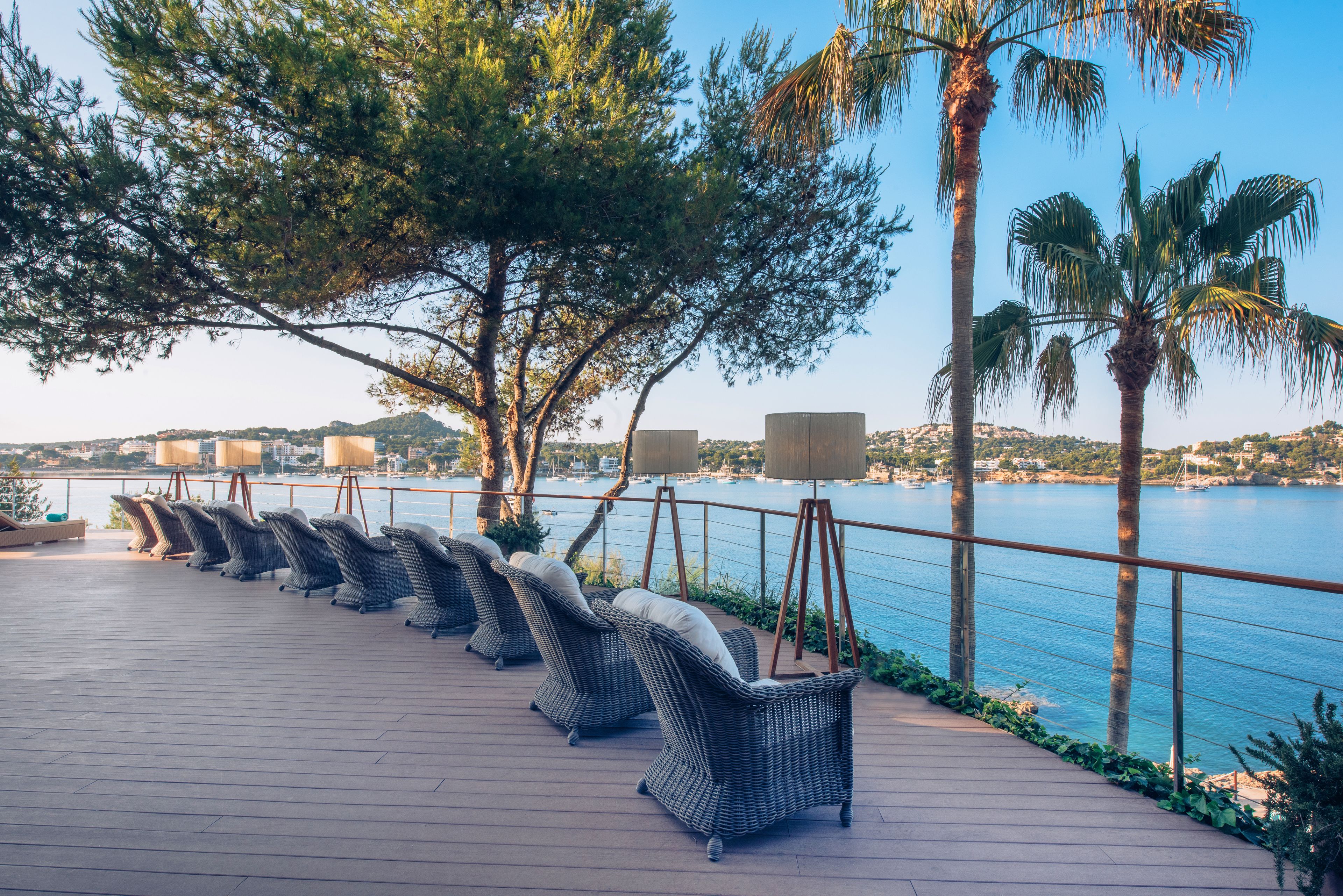 Una terraza con sillas de mimbre y vista al mar.
