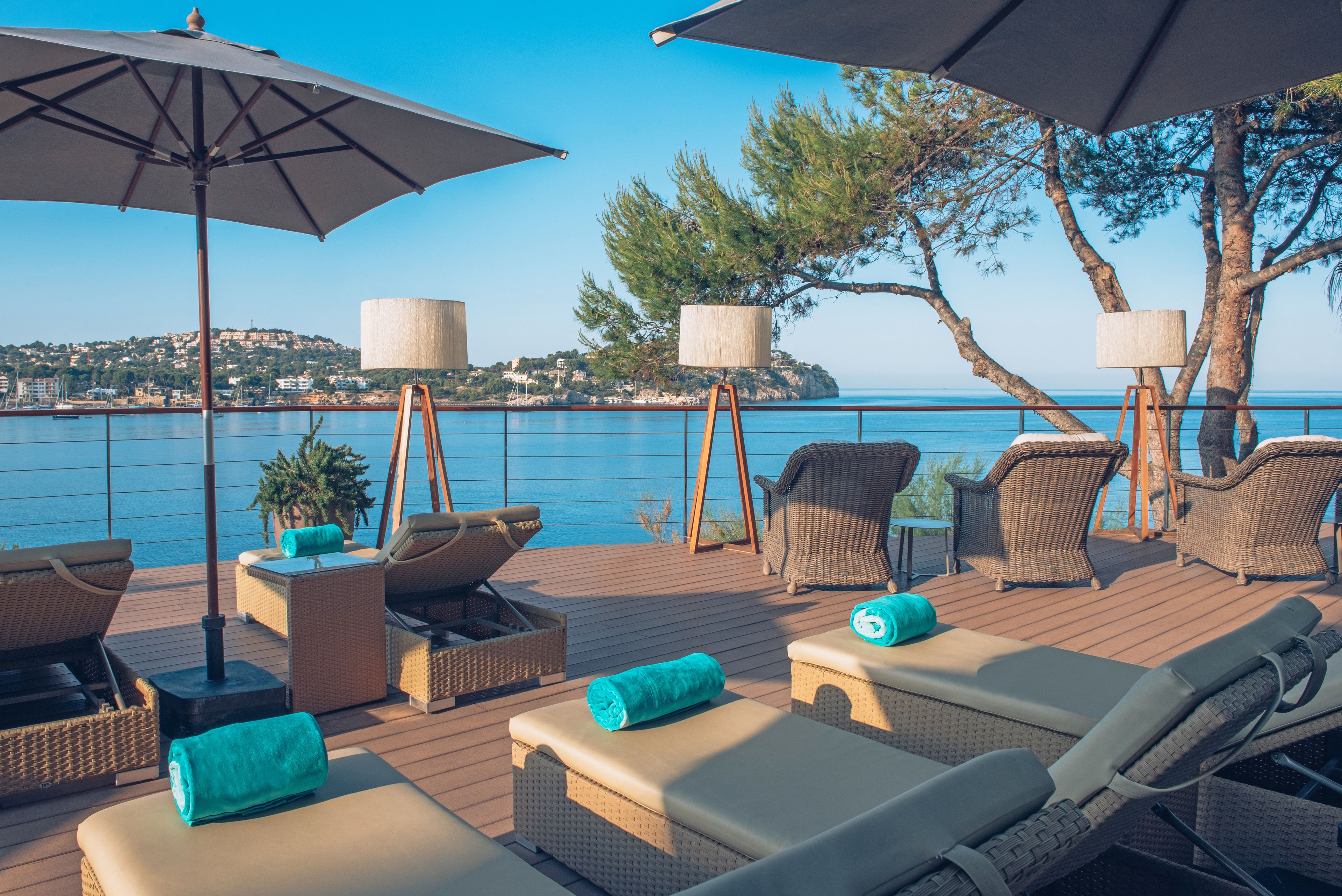 A deck with lounge chairs, umbrellas, and a view of the sea.