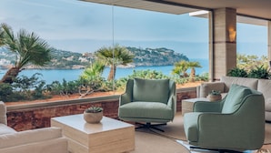 A modern outdoor seating area with a view of the sea and hills. - Iberostar Selection Jardín del Sol Suites - Adults Only (Calvia)