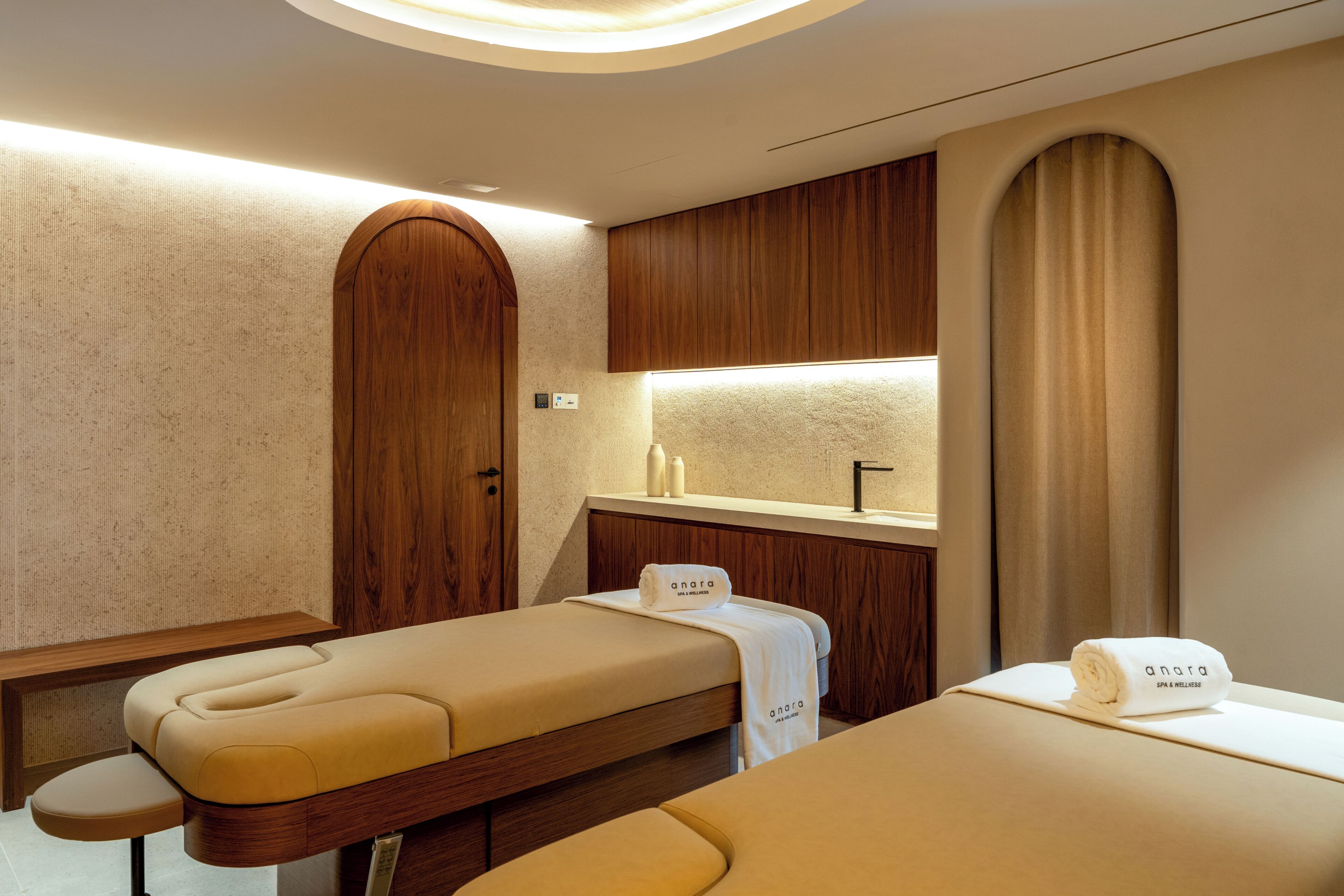 Ein Zimmer mit zwei Betten, Holzwandverkleidung, einem kleinen Schminktischchen mit Spiegel und einem Handtuch mit Branding.