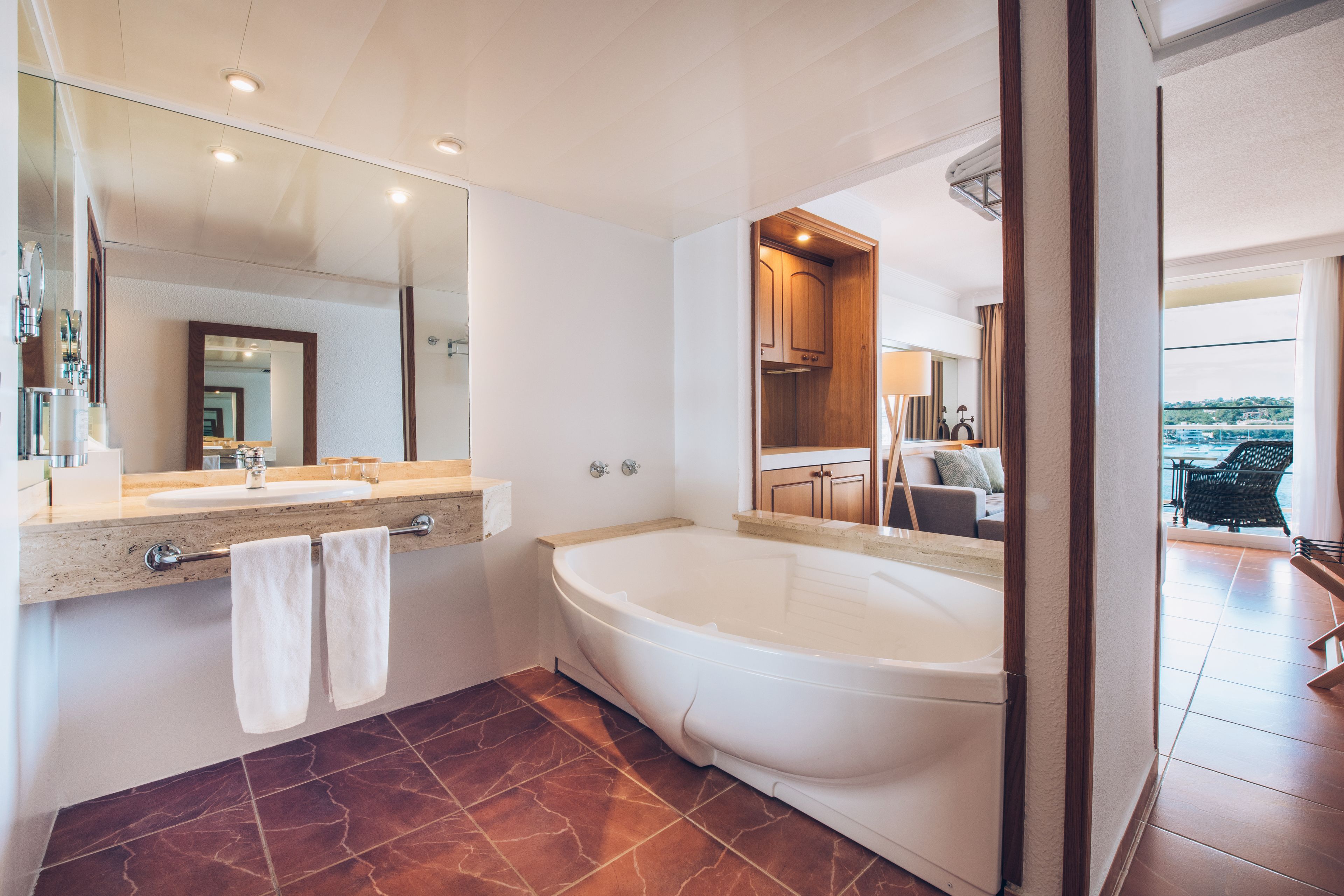 A modern bathroom with a large bathtub, a double sink, and a large mirror.