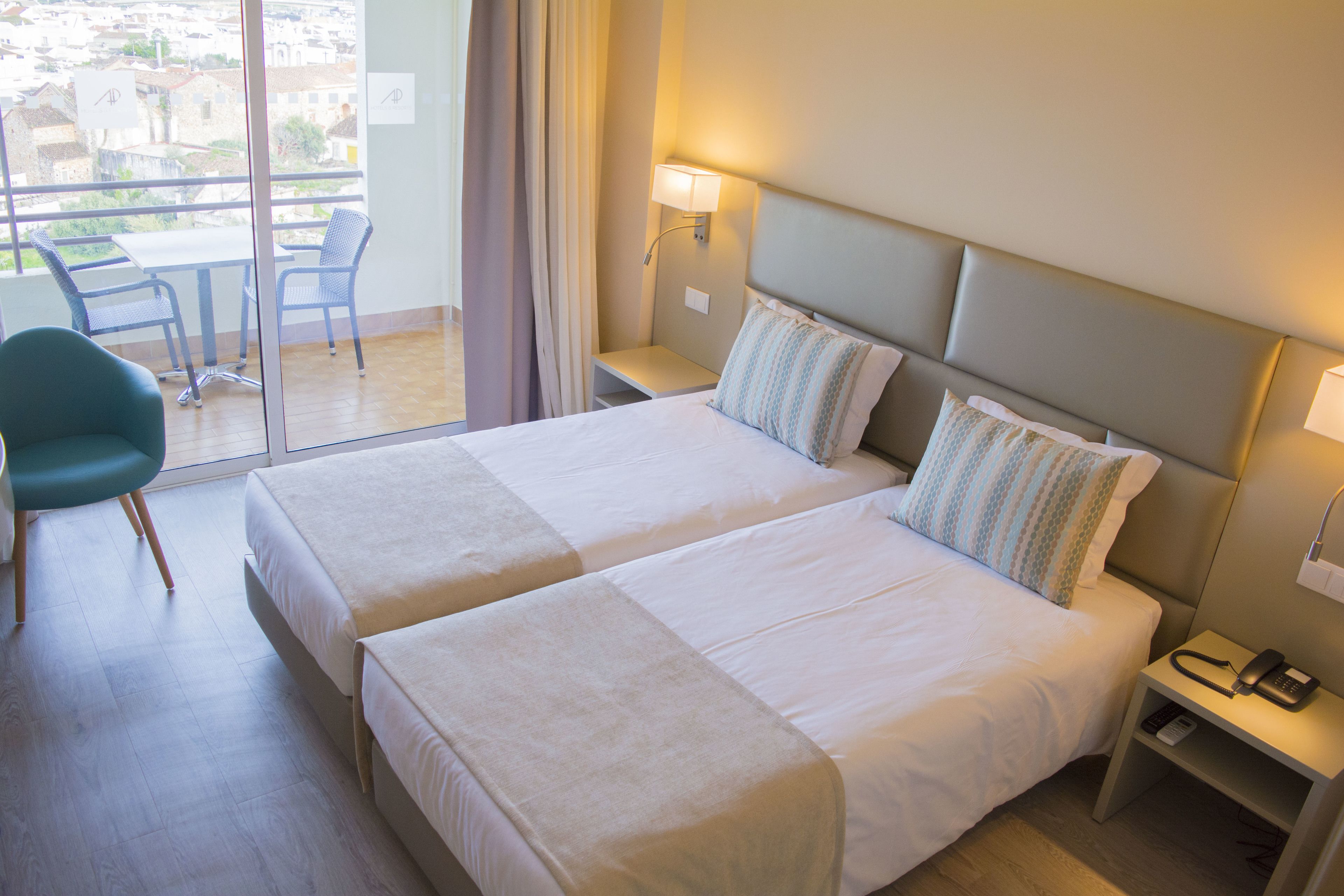 A hotel room with two beds, a desk, and a chair.