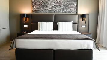Una habitación de hotel moderna con una cama grande, dos mesitas de noche y una obra de arte colgada en la pared.