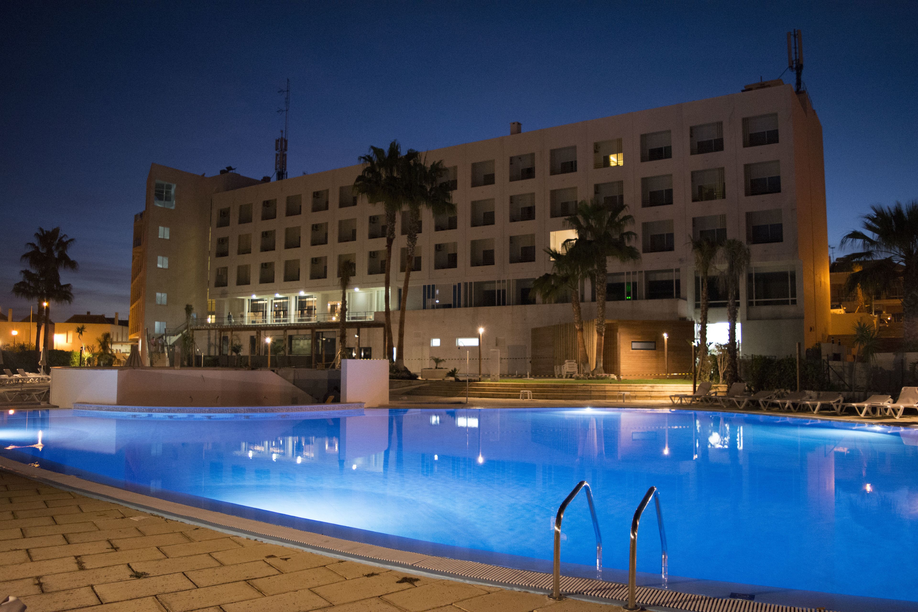 A swimming pool with a clear view of a hotel building in the background.