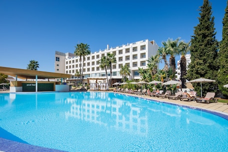 Una piscina techada, sombrillas, sillones reclinables de piscina