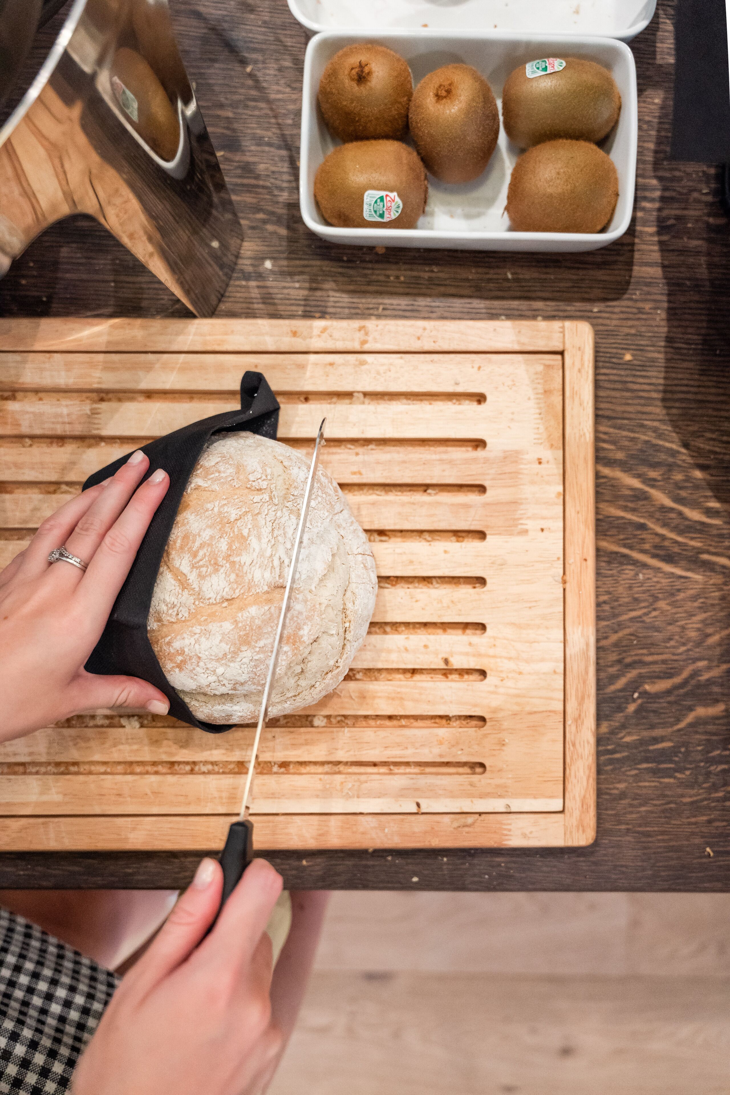 Una persona cortando un pan en una tabla de madera.