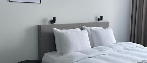 A modern hotel room with a neatly made bed, a small side table, and a framed picture on the wall.