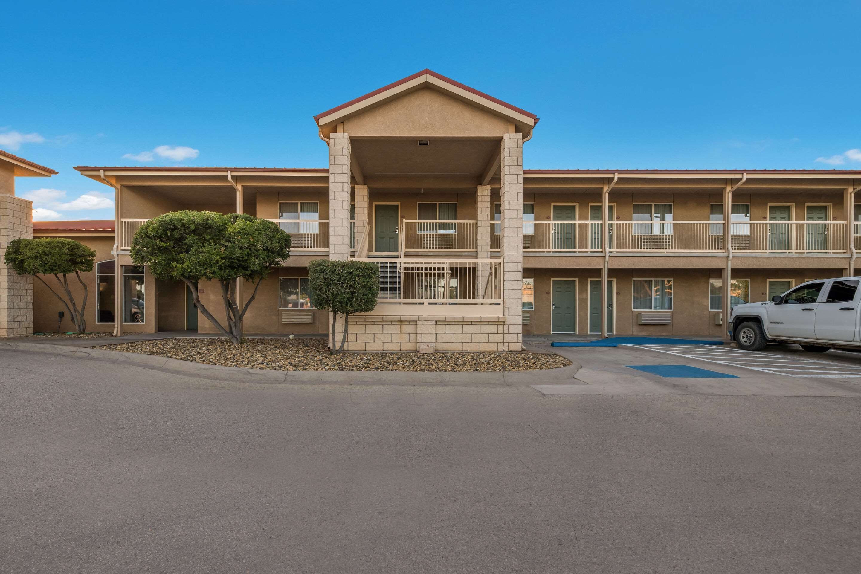 A multi-story motel with a central entrance, balconies, and a parking area.