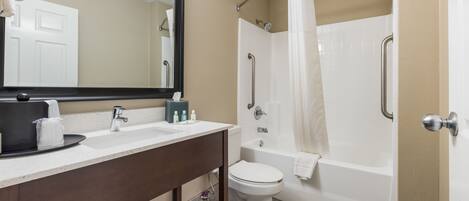 A bathroom with a sink, mirror, toilet, and a walk-in shower.