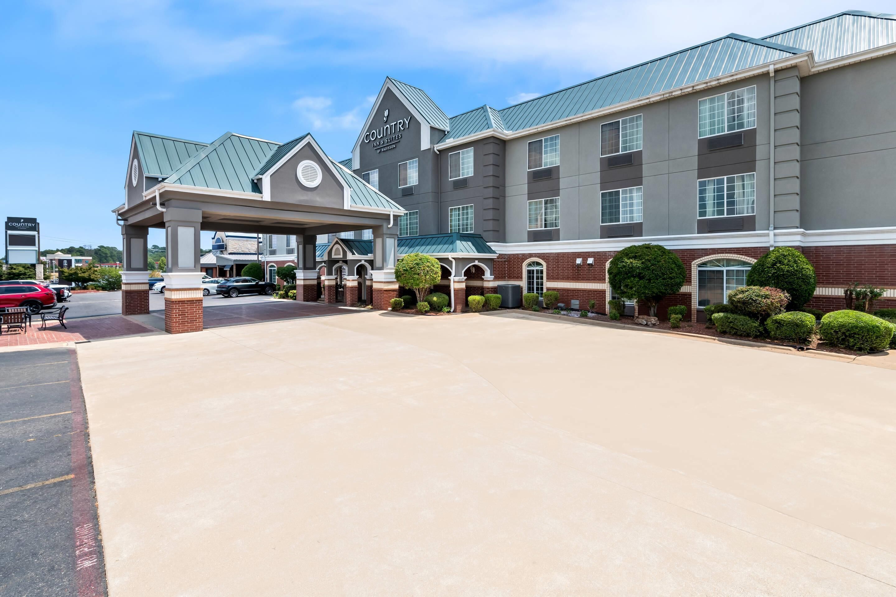 A hotel with a covered entrance, multiple floors, and a brick facade.