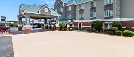 A hotel with a covered entrance, multiple floors, and a brick facade.