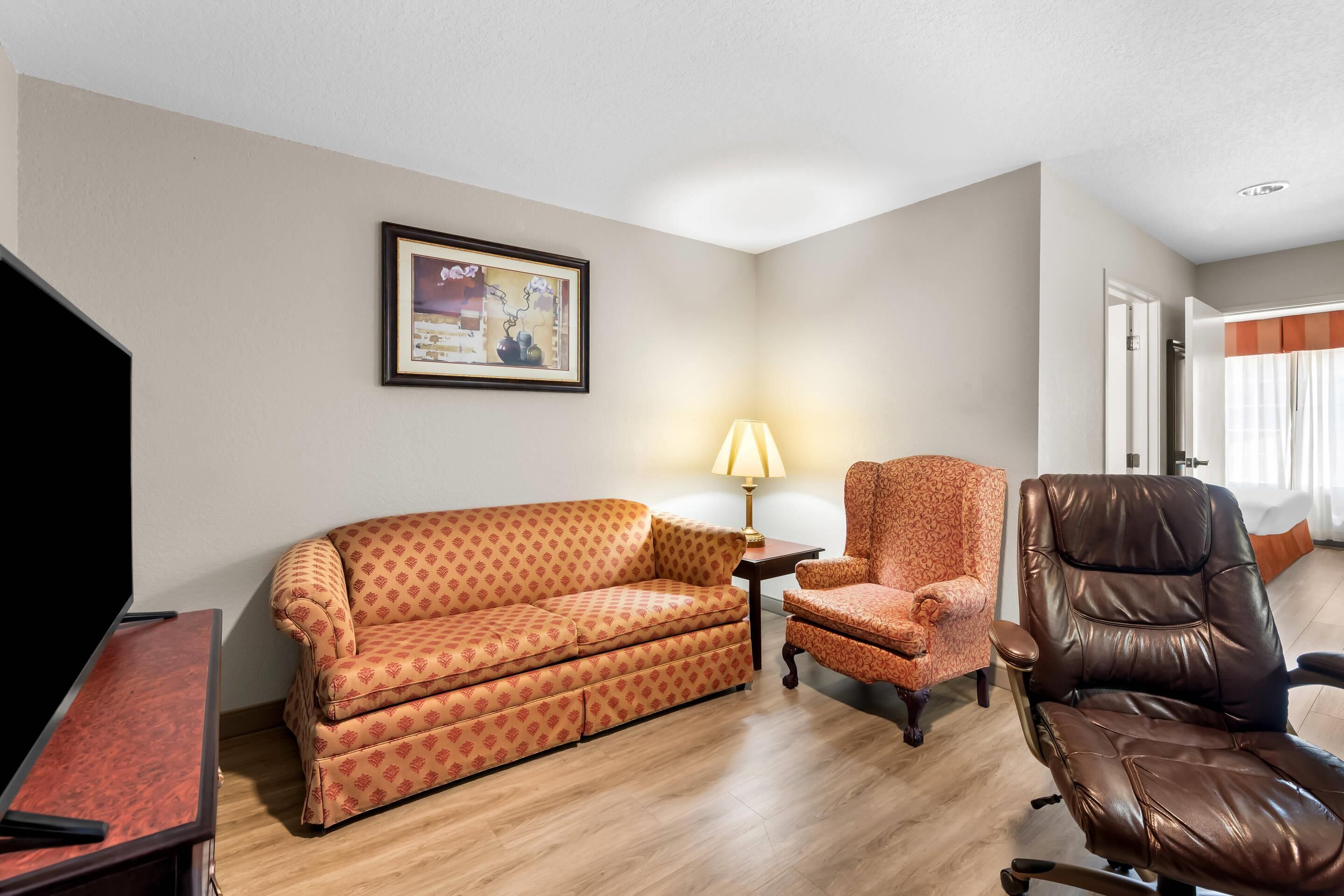 Una sala de estar con sofá, sillón y mueble para televisión.
