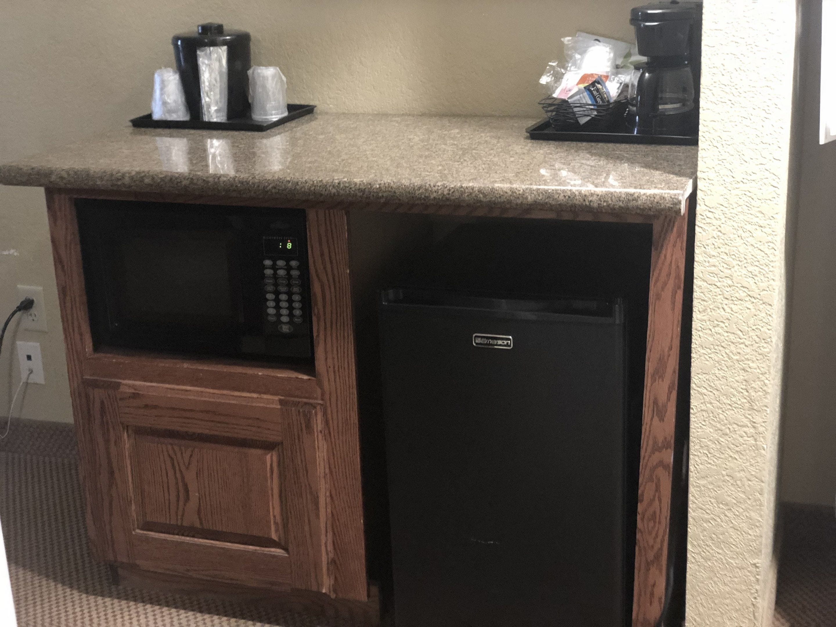 A kitchenette with a microwave, coffee maker, and refrigerator.