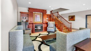 A living room with a fireplace, a staircase, and a sofa. - Country Inn & Suites by Radisson, Hot Springs, AR (Hot Springs)