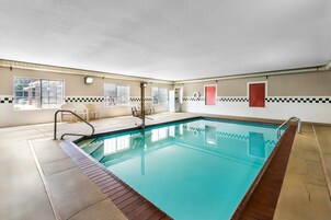 Una piscina con solárium de baldosas, un vestuario y un ventanal con vistas.