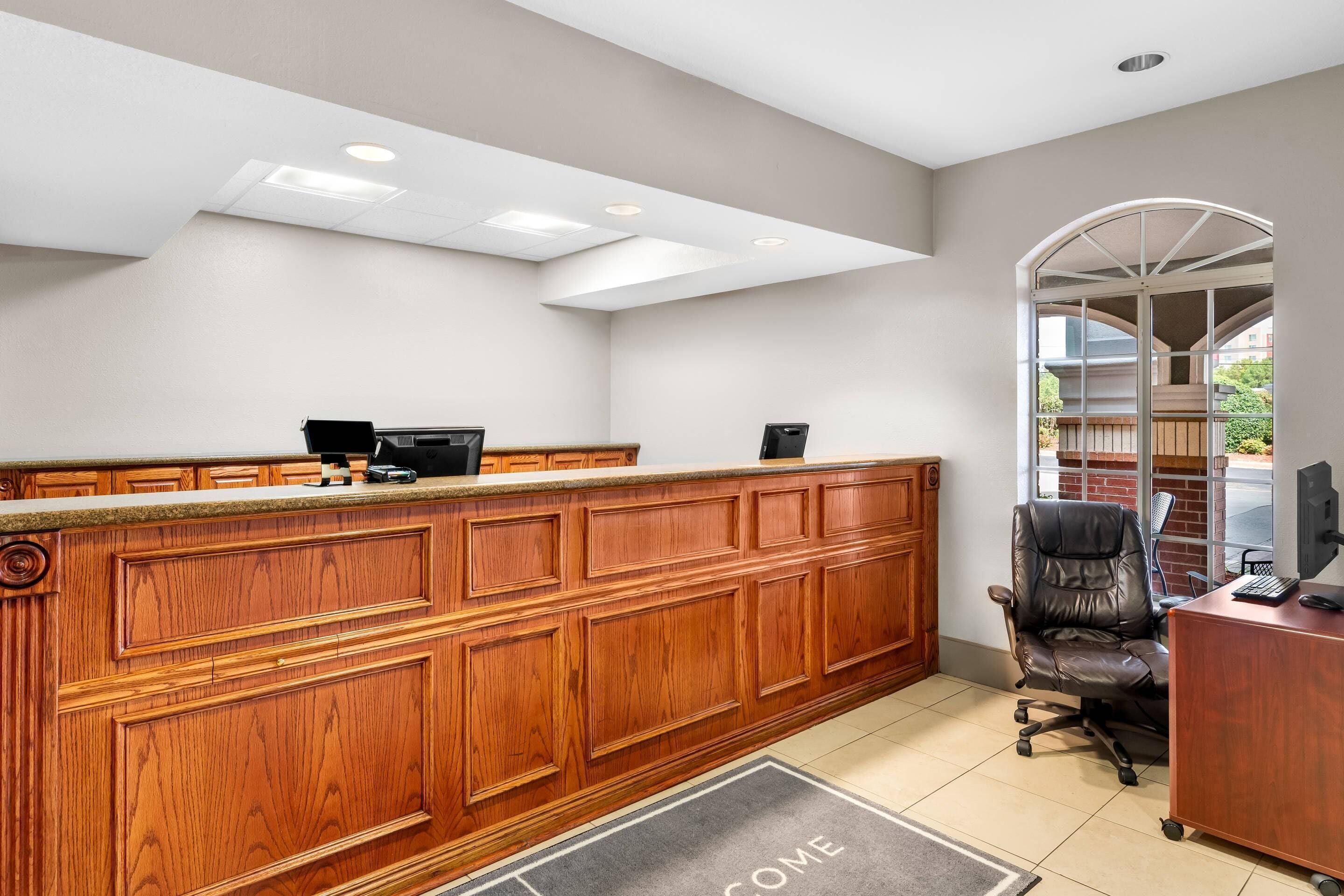 Un mostrador de recepción con detalles de madera, una computadora y una silla.