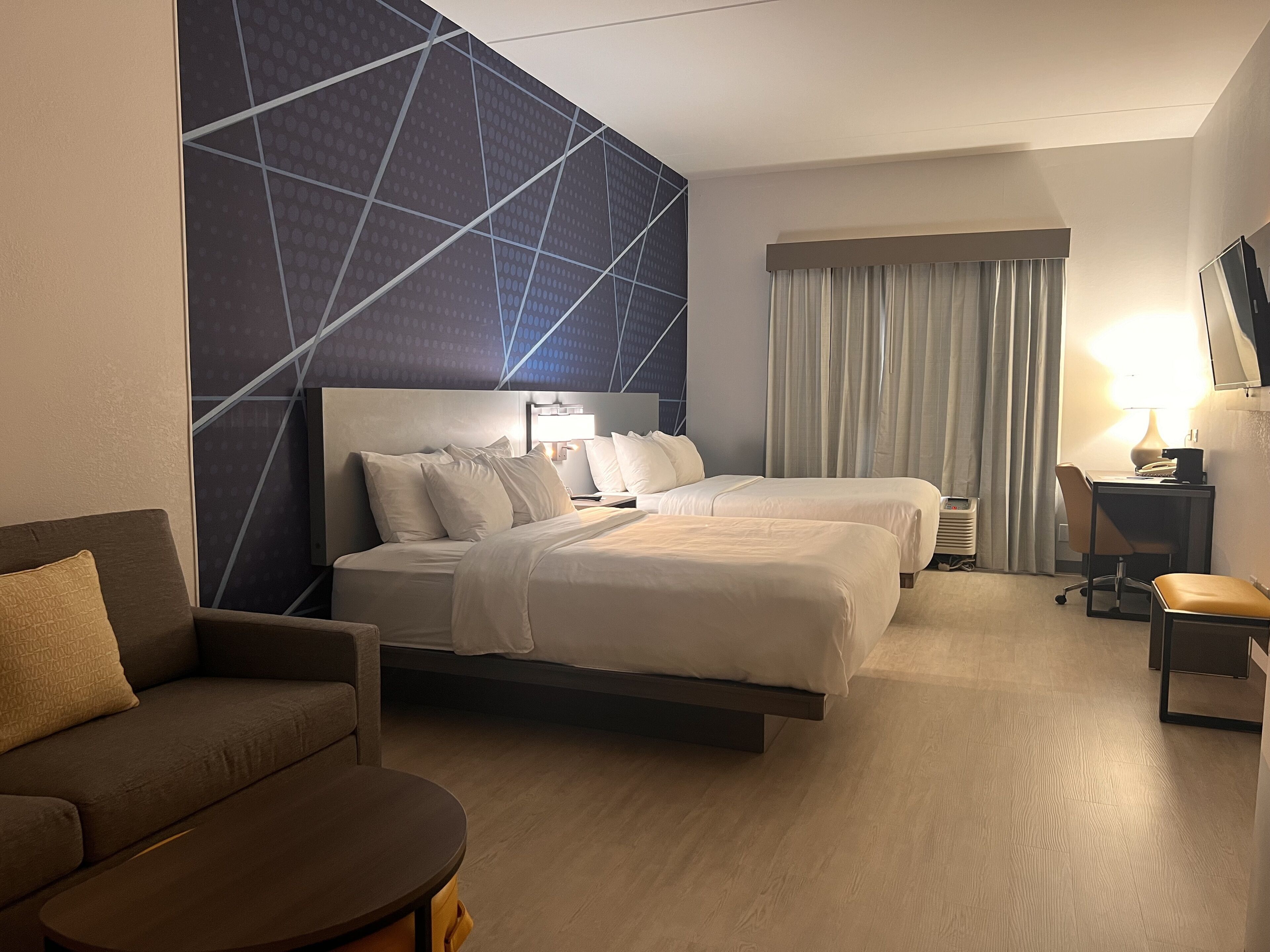 Una habitación de hotel con dos camas, un sofá, un escritorio y una televisión.