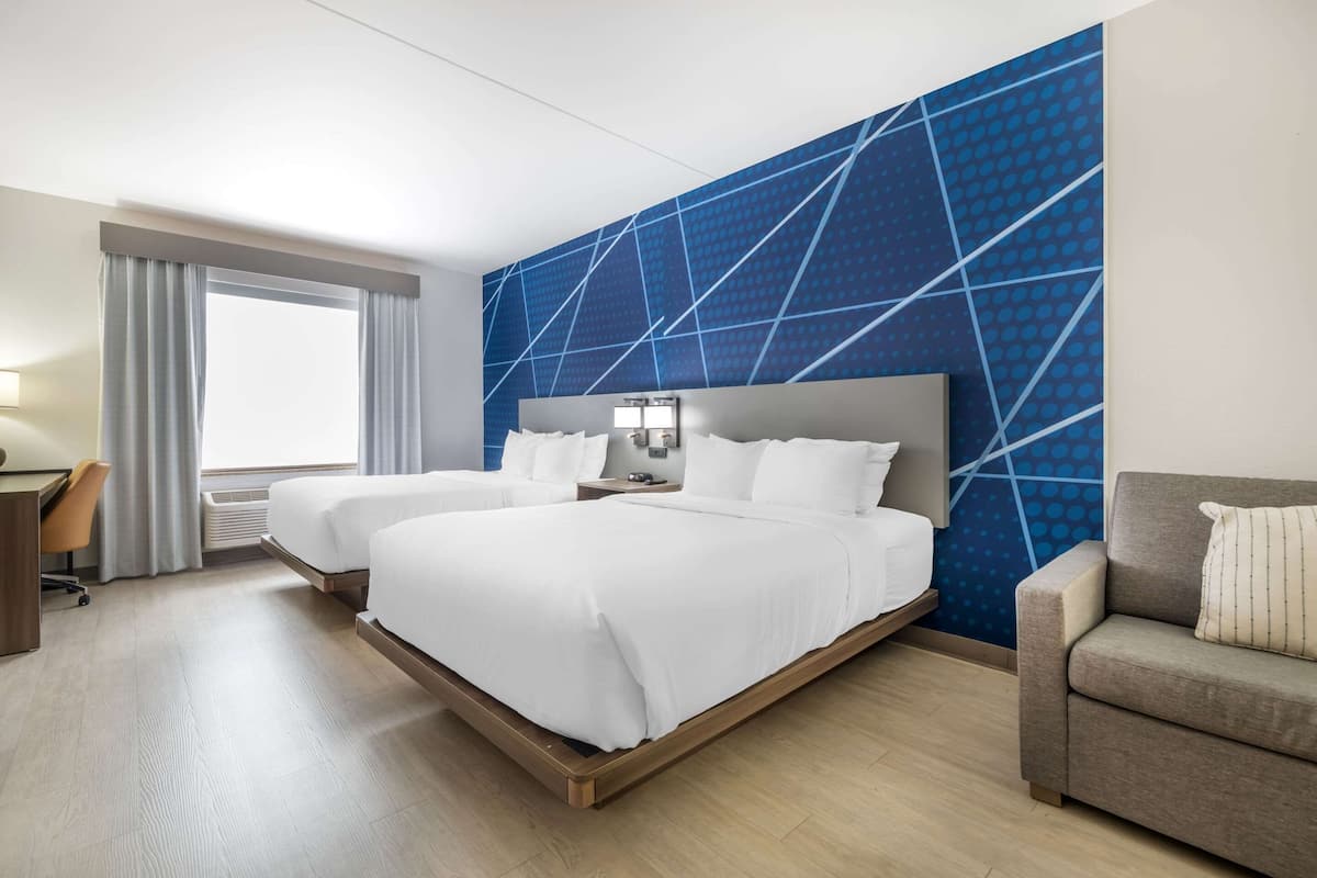 Ein Hotelzimmer mit zwei Betten, einem Schreibtisch, einem Sessel und einer Couch.