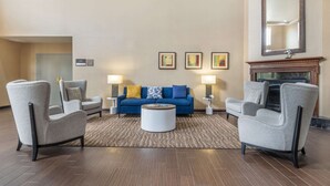 Ein modernes Wohnzimmer mit einem blauen Sofa, zwei Sesseln, einem Couchtisch und einem Kamin.