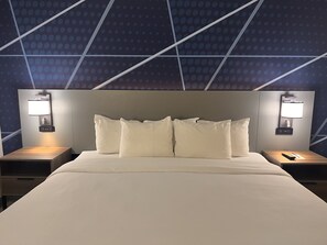 A hotel room with a large bed, two bedside tables, and a wall-mounted lamp. - Comfort Suites Louisville Airport (Louisville)