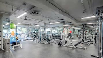A gym with various exercise equipment, large windows, and a mirrored wall.