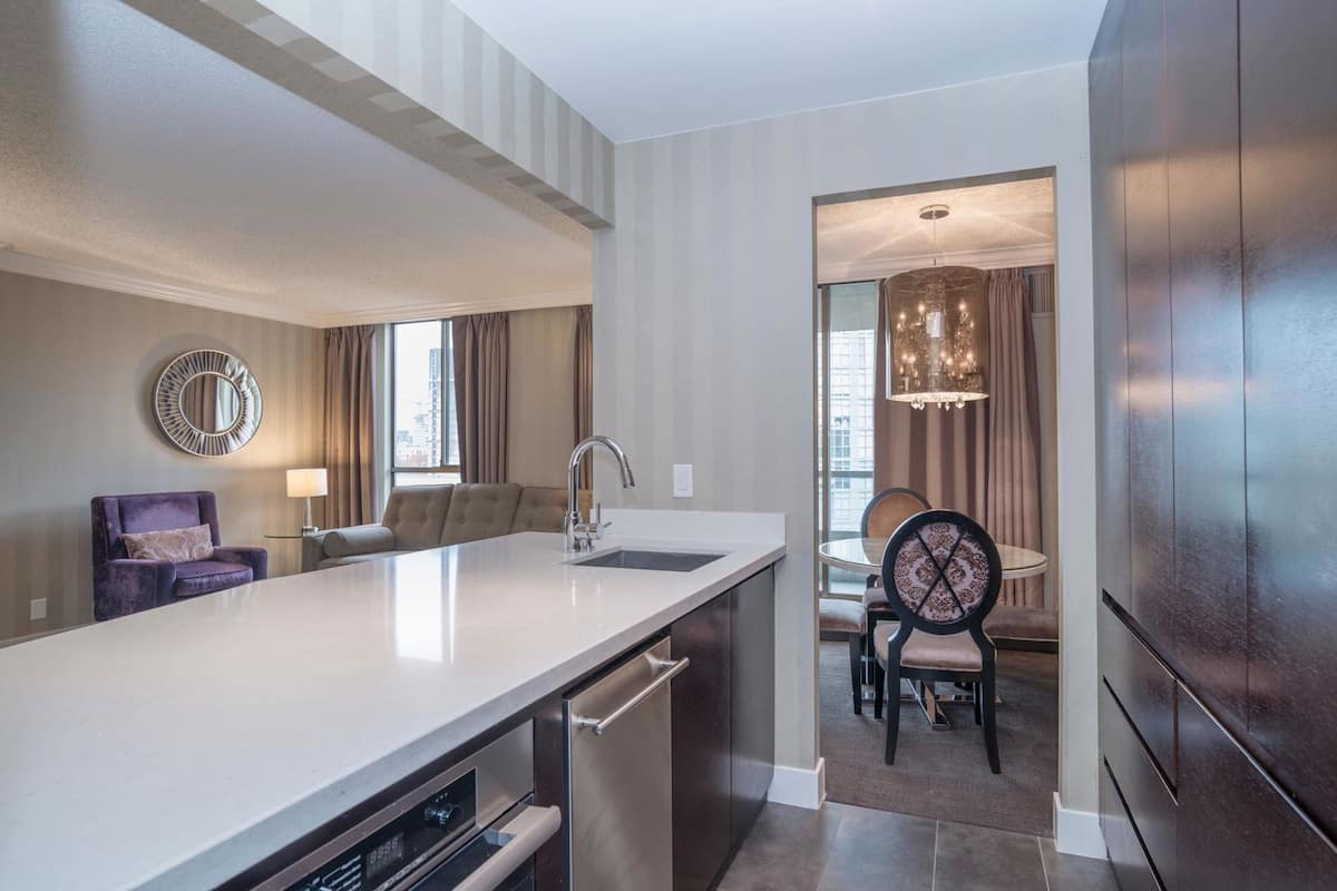 A modern kitchen with a large island, a dining area with a chandelier, and a view of the city.