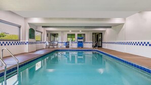 A swimming pool with a tiled edge, a wooden deck, and a seating area with chairs and a table. - La Quinta Inn & Suites by Wyndham Batavia (Batavia)