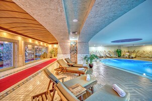 An indoor swimming pool area with lounge chairs, a red carpet, and a tiled floor.