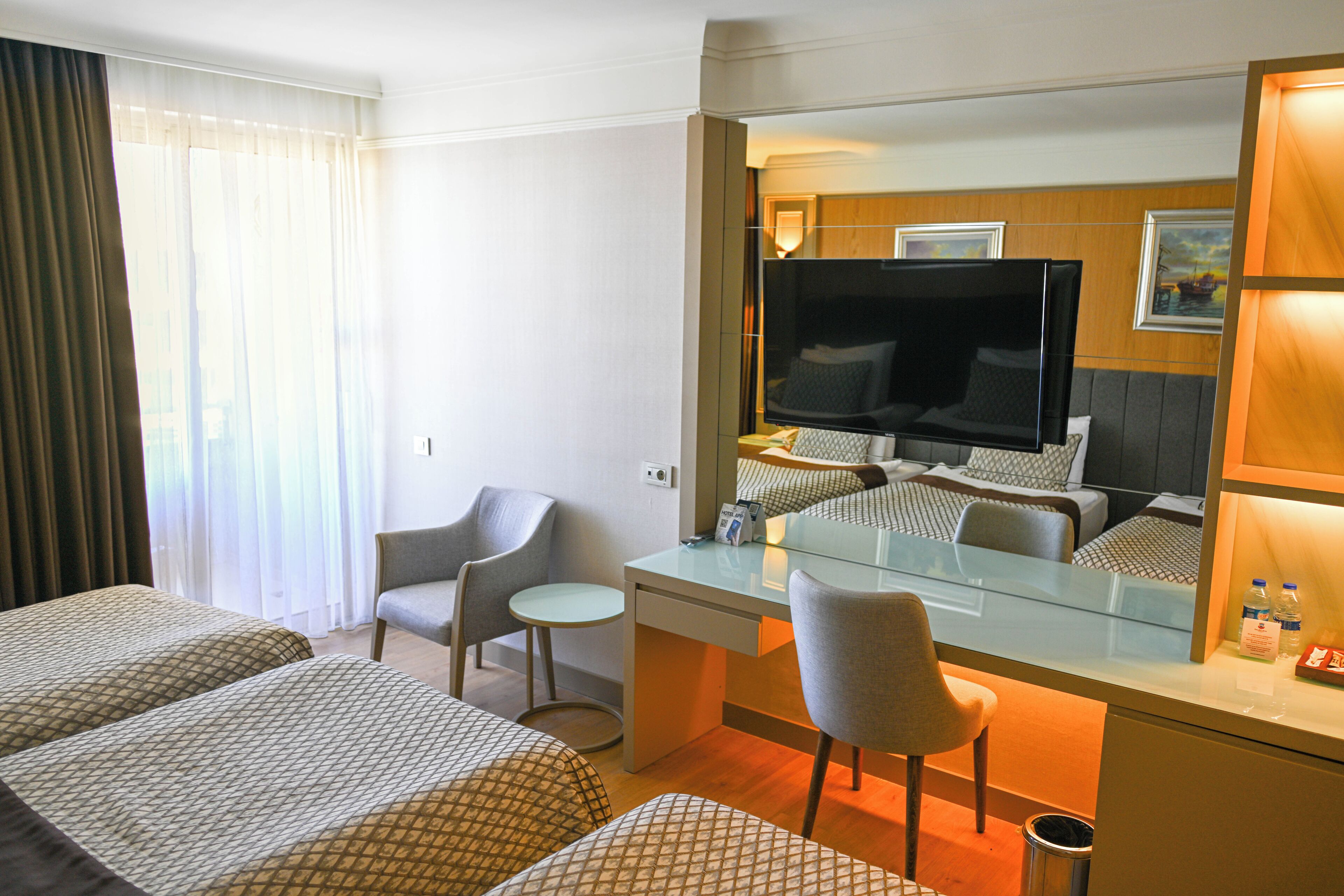 Une chambre d’hôtel avec deux lits, un bureau, une chaise, une télévision et une petite table.