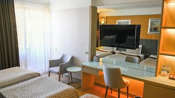 Une chambre d’hôtel avec deux lits, un bureau, une chaise, une télévision et une petite table.