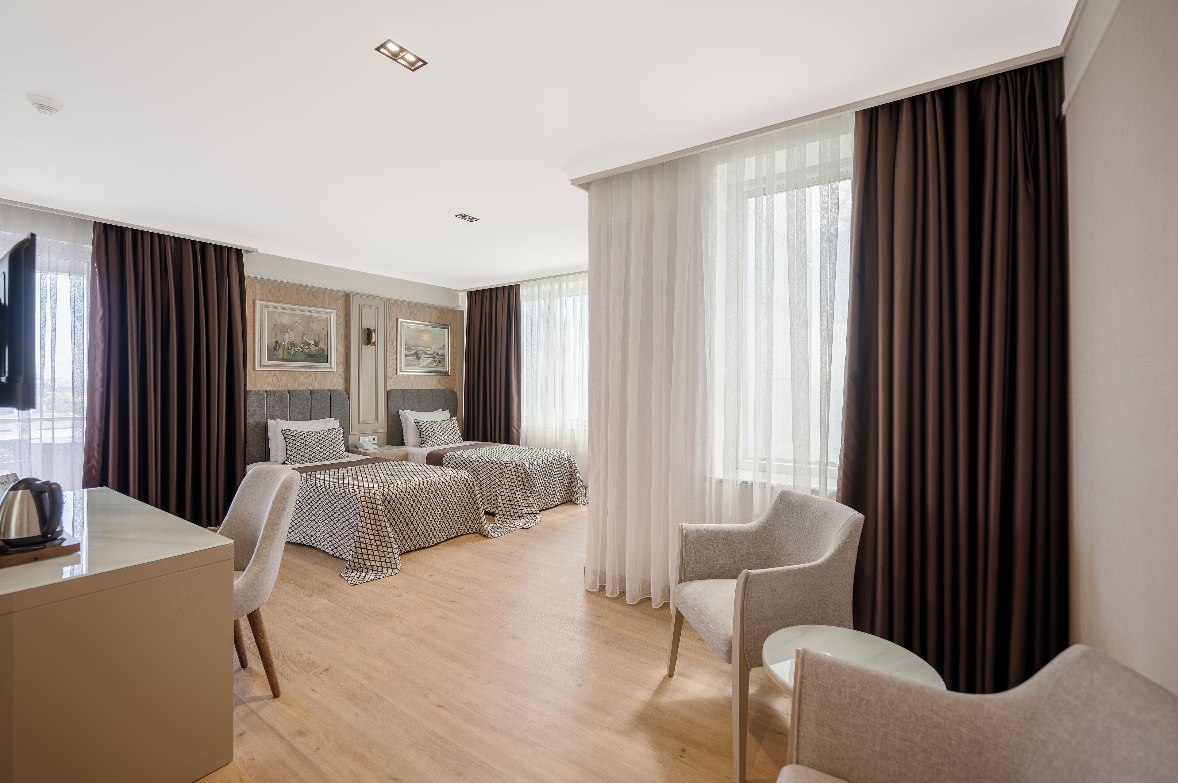 Een hotelkamer met een bed, twee stoelen, een bureau en een televisie.