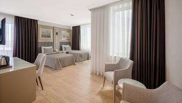 Een hotelkamer met een bed, twee stoelen, een bureau en een televisie.