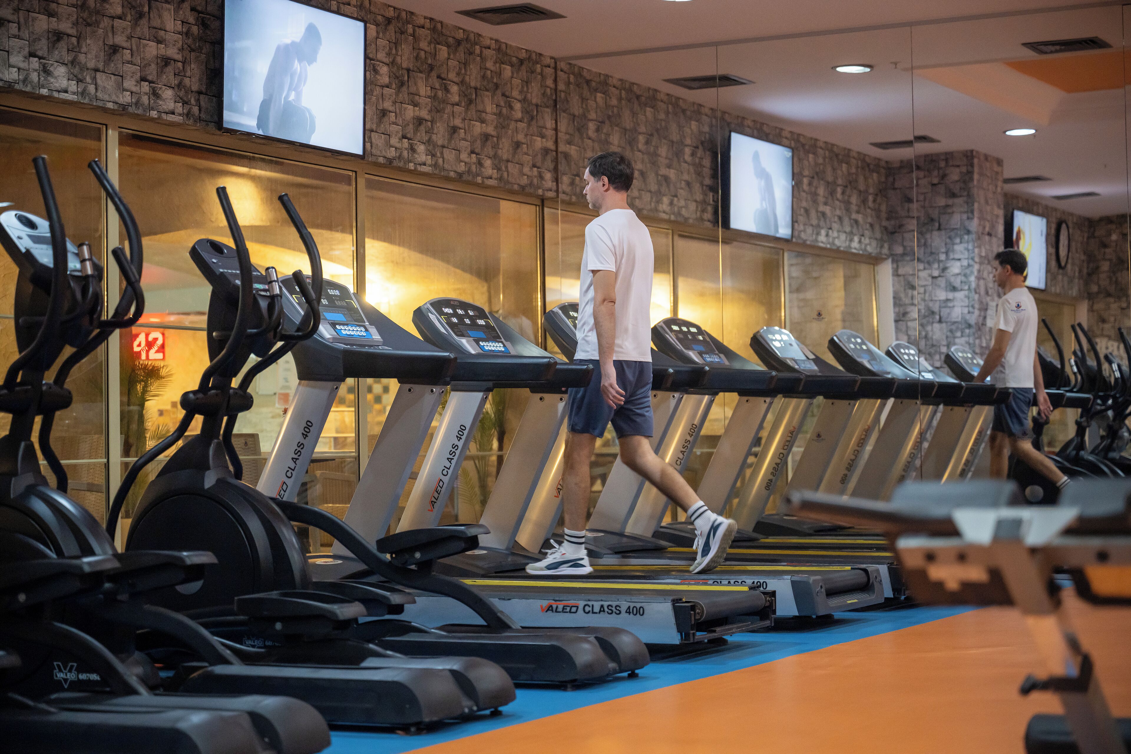 A gym with treadmills, exercise bikes, and a mirrored wall.