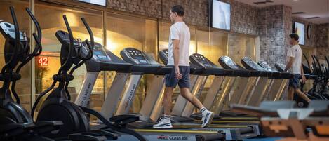 A gym with treadmills, exercise bikes, and a mirrored wall.