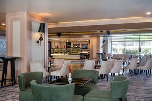 Un vestíbulo de hotel con áreas de estar, un mostrador de recepción y vistas al exterior.