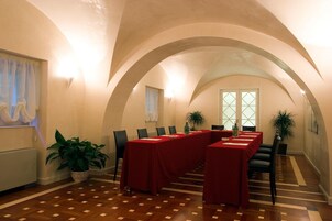 Un salón de conferencias con una larga mesa, sillas y plantas en macetas.