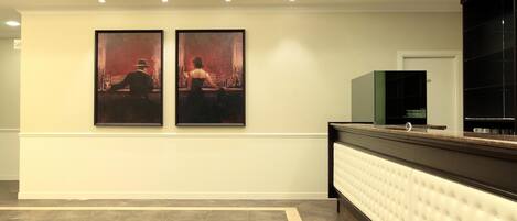 A reception area with a marble floor, a white reception desk, and two framed artworks on the wall.