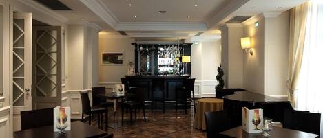 A hotel lobby with a bar area, seating arrangements, and a decorative wall.