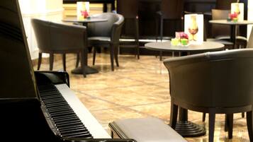 A piano in a restaurant setting with tables and chairs.